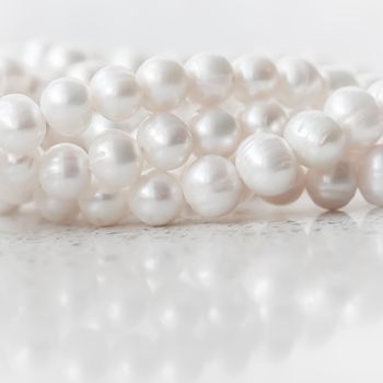 Nature white string of pearls on marble background in soft focus, with highlights