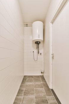 View of a bathroom with a boiler system surrounded by white tiles in a modern house