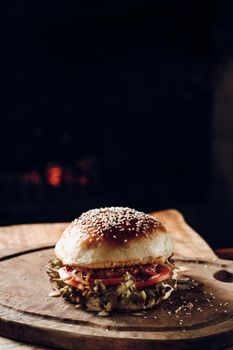 Juicy hamburger on a wooden stand on a black background. High quality photo
