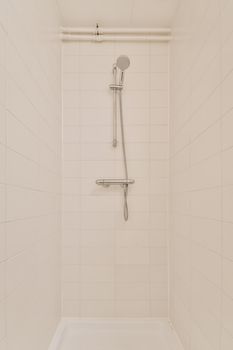 View of the bathroom with shower surrounded by white tiles in a modern house