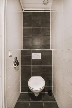 View of a bathroom with a hinged toilet surrounded by white and black tiles in a modern house