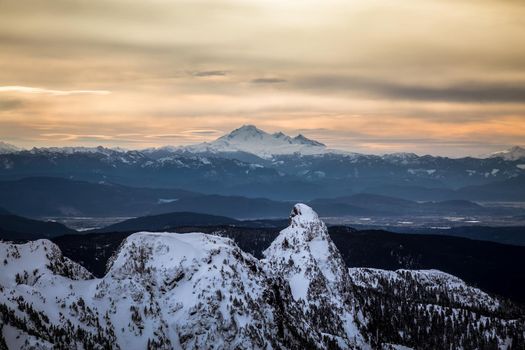 Aerial landscape view of Golden Ears Mountain with Mount Baker in the background. Picture taken near Pitt Meadows in Vancouver Lower Mainland, British Columbia, Canada, during a cloudy winter morning.