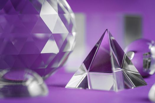 Crystal prism refracting light, magic crystals and pyramid, sphere and cube on purple background. Spiritual healing crystal practice. Feng Shui, good energy flow concept, esoteric background..