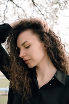 portrait of curly brunette woman in red coat in the park