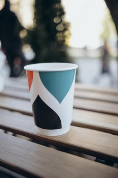 Paper cup with tea coffee drink on a wooden table against the background plant and a green wall. Zero West Concept.