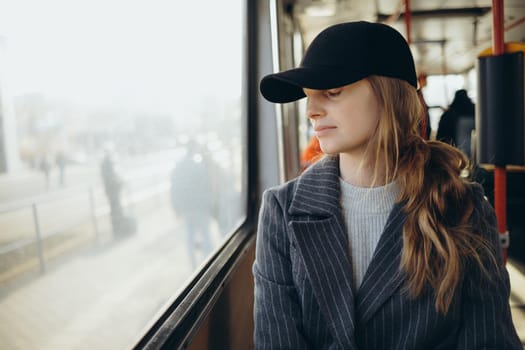 Young woman sadly looking out bus window, and wear earphones