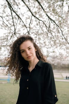 portrait of curly brunette woman in red coat in the park