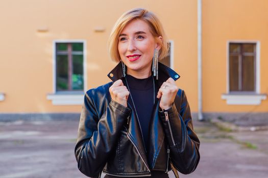 Street fashion concept - closeup portrait of a pretty girl wearing leather jacket outdoors.