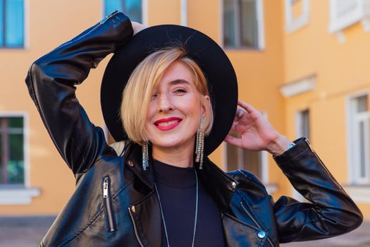 Street fashion concept - closeup portrait of a pretty girl wearing hat and leather jacket outdoors.