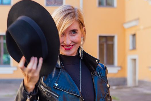 Street fashion concept - closeup portrait of a pretty girl wearing hat and leather jacket outdoors.