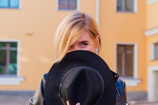 Street fashion concept - closeup portrait of a pretty girl wearing hat and leather jacket outdoors.