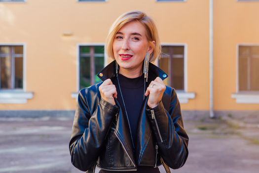 Street fashion concept - closeup portrait of a pretty girl wearing leather jacket outdoors.