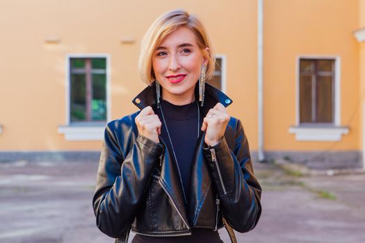 Street fashion concept - closeup portrait of a pretty girl wearing leather jacket outdoors.