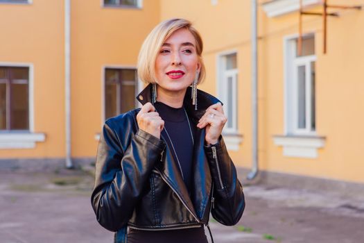 Street fashion concept - closeup portrait of a pretty girl wearing leather jacket outdoors.