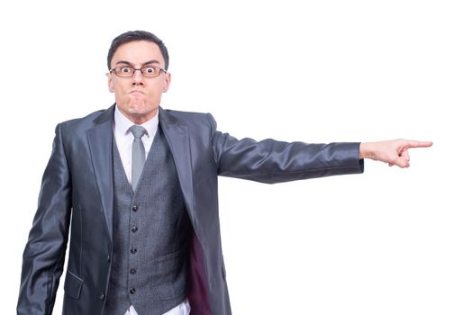 Anxious male entrepreneur in formal suit and glasses pointing aside and looking at camera while standing isolated on white background