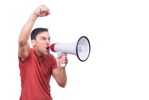 Furious man raising arm with fist and looking away while shouting in megaphone isolated on white background