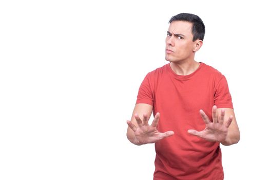 Isolated discontent male in casual clothes looking at camera while demonstrating stop gesture with both hands on white background