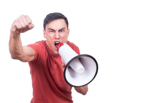 Isolated male model in red t shirt shouting in loudspeaker with raised fist against white background and looking at camera