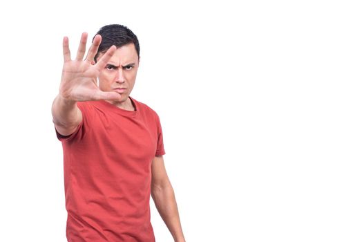 Isolated serious man in red t shirt show gesticulating stop sign and looking at camera in studio