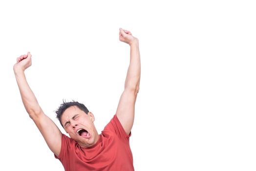 Sleepy man in t shirt with closed eyes yawning and stretching arms while standing isolated on white background in light studio