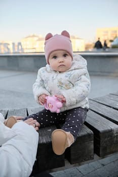 Young mother with her cute baby on bench in park