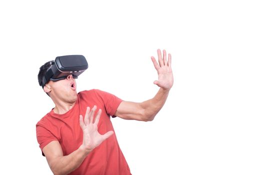 Astonished male gamer with opened mouth in modern VR goggles exploring virtual reality while standing isolated on white background in light studio