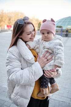 Mother holding baby smiling to camera. Real life authentic casual mom looking to camera holding infant