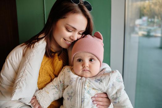 Mother holding baby smiling to camera. Real life authentic casual mom looking to camera holding infant