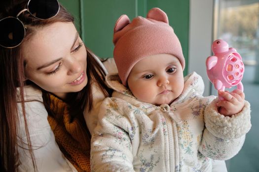 Mother holding baby smiling to camera. Real life authentic casual mom looking to camera holding infant