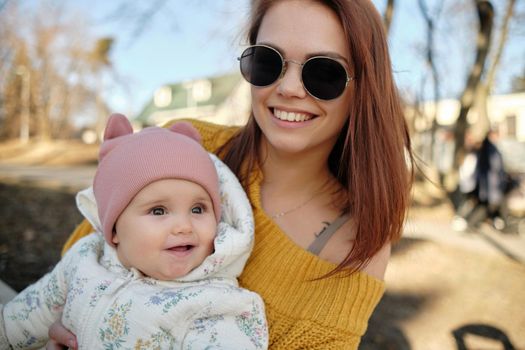 Mother holding baby smiling to camera. Real life authentic casual mom looking to camera holding infant