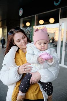 Mother holding baby smiling to camera. Real life authentic casual mom looking to camera holding infant