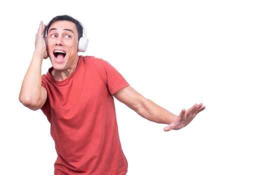 Isolated man in red t shirt dancing happily while listening to music from headphones on white background in studio