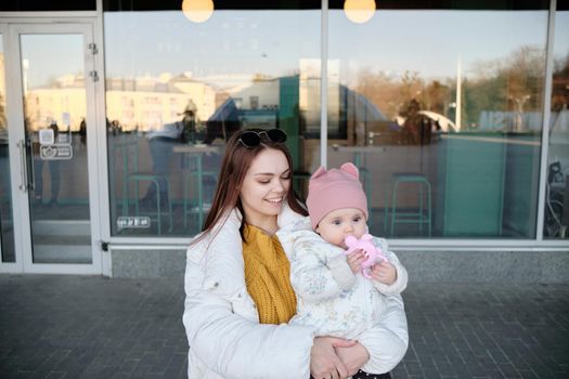 Mother holding baby smiling to camera. Real life authentic casual mom looking to camera holding infant