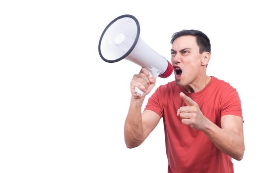 Excited male yelling in megaphone and pointing away with finger on white backdrop in studio