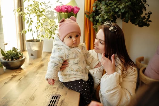 young and pretty mother sitting at the cafe with her little daughter sunny