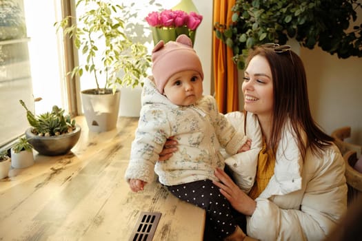 young and pretty mother sitting at the cafe with her little daughter sunny