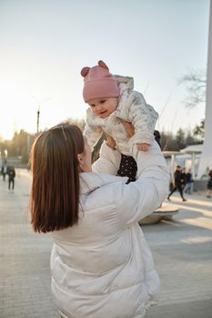 happy harmonious family outdoors. mother throws baby up, laughing and playing in the summer on the nature