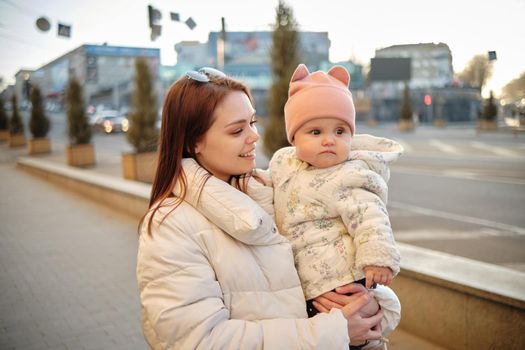 Mother holding baby smiling to camera. Real life authentic casual mom looking to camera holding infant