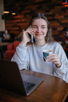 freelance woman happy working in a cafe remotely brunette and talking by the phone