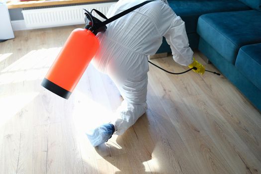 Close-up of man in hazmats making disinfection in flat. Professional cleaning with disinfectant spray. Coronavirus disinfection concept