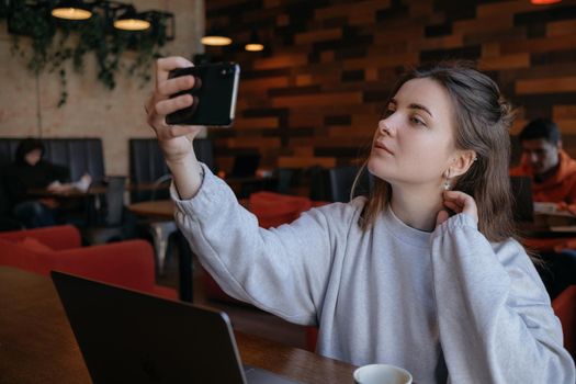 Smiling woman sitting on kitchen sofa talking by videocall dating online looking at phone. Video blogger vlogger recording vlog at home. Lifestyle vlogging concept, head shot portrait