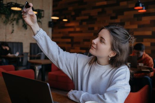 Smiling woman sitting on kitchen sofa talking by videocall dating online looking at phone. Video blogger vlogger recording vlog at home. Lifestyle vlogging concept, head shot portrait