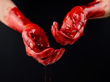 Women's hands in blood on a black background