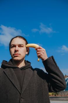 young gay hipster make banana suicide at the street. sky