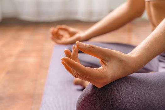 Young woman meditating in the lotus pose at home. Practicing yoga indoors. Harmony, yoga practice, balance, meditation, relaxation at home, healthy lifestyle concept