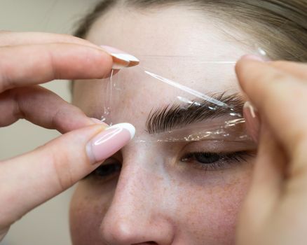 The master uses a plastic film during lamination of the eyebrows