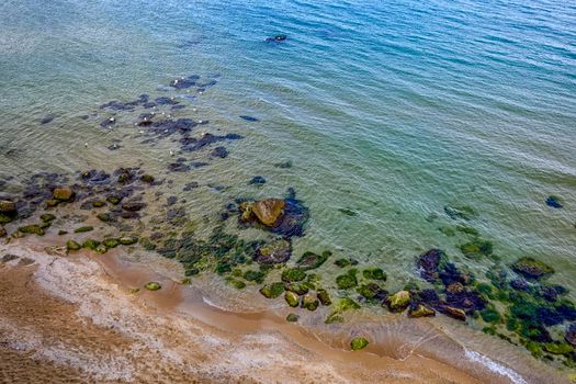 Aerial drone view of crystal clear lagoon sea water surface with rocks and seagulls