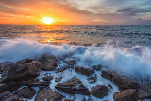 Stunning seascape with the colorful sunrise sky and beauty waves at the rocky coastline of the Black Sea