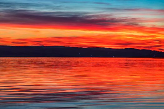Stunning colorful red sunset at the sea with dramatic clouds