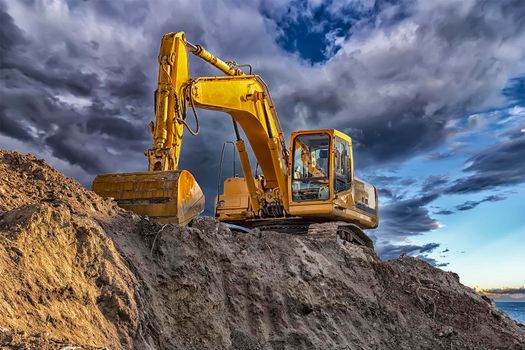A stopping yellow excavator at an incredibly beautiful sunset